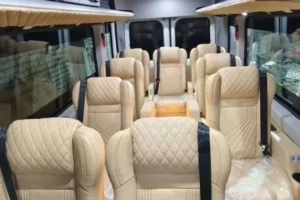 Luxury interior of 17-seater Urbania corporate van featuring quilted pushback seats, spacious aisle, and premium comfort for business travel and small group journeys.
