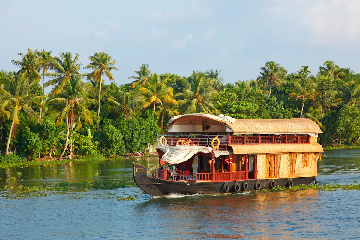 Serene Kerala 4 Star Family Holiday Package featuring a comfortable houseboat cruise through Kerala’s calm backwaters surrounded by coconut palms and lush greenery.