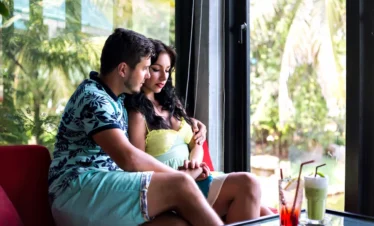 Kerala Short Trip Itinerary showing a couple relaxing indoors with tropical greenery outside, representing a peaceful Kerala getaway