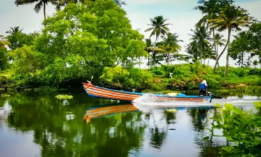 Kumarakom village backwaters with traditional canoe, palm trees, and peaceful riverside scenery